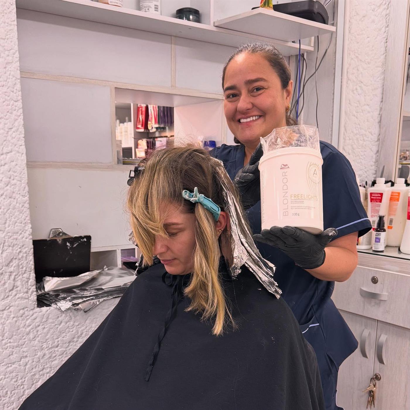 La estilista de Alextilo aplicando color con papel aluminio, sonriendo en el salón
