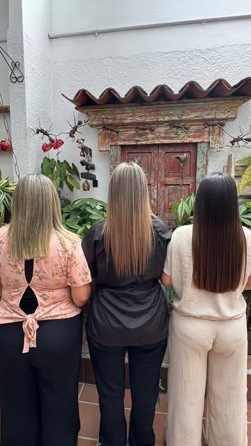 Tres clientas de espaldas con cabello liso frente a una puerta colonial